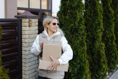 Kurye, evin kapısının önüne iki karton kutu getiriyor. Mahalledeki müşterilerin siparişlerini yerine getiriyor.