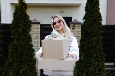 Genç kurye, neşeli bir müşteriye büyük bir paket teslim ediyor. Neşeli bir gülümsemeyle günü aydınlatıyor.