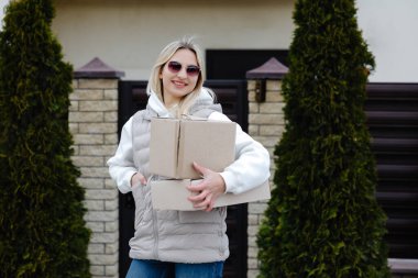 Genç kurye, neşeli bir müşteriye büyük bir paket teslim ediyor. Neşeli bir gülümsemeyle günü aydınlatıyor.