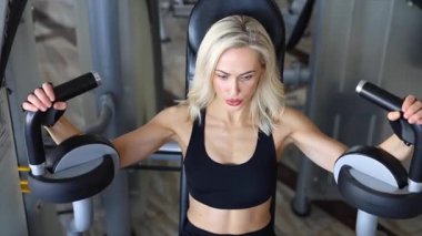 Kararlı sporcu kadın göğüs kasları için spor aletleri kullanıyor.