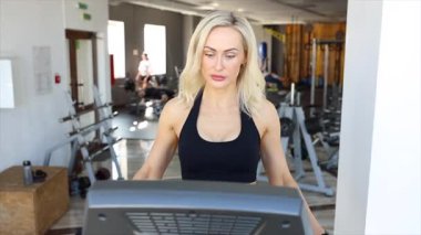 Modern spor salonunda koşu bandında koşan kararlı bir sporcu.