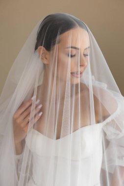 Bir fotoğraf çekimi için şık bir gelin, beyaz bir gelinlik ve duvak giyiyor, gelin modasını gözler önüne seriyor.