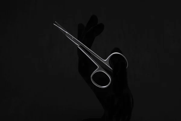 tırnak makası elinde siyah arkaplanda                    
