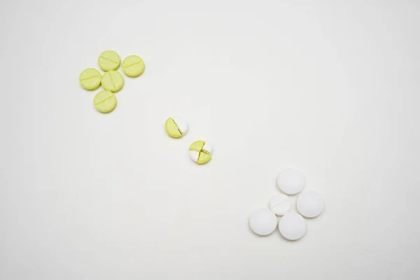 Beyaz arka planda haplar, haplı kompozisyon, yarım tablet, sarı ve beyaz haplar.