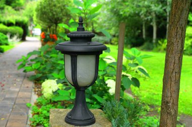 Güzel tasarlanmış bir bahçe bahçesinde metal bir lamba.