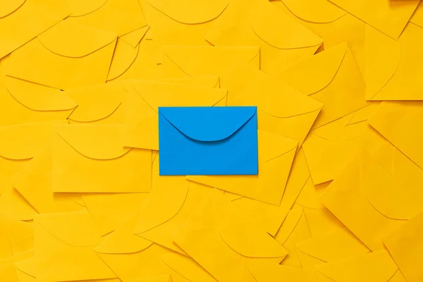 Masaya saçılmış sarı zarflar, beyaz bir kağıt üzerinde metin için boşluk, ve mavi bir zarf vurgulanmış, üst görünüm.