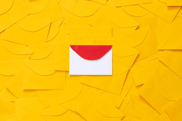 Masaya saçılmış sarı zarflar, beyaz bir kağıttaki yazı için boşluk ve işaretlenmiş kırmızı bir zarf. Üst görünüm.