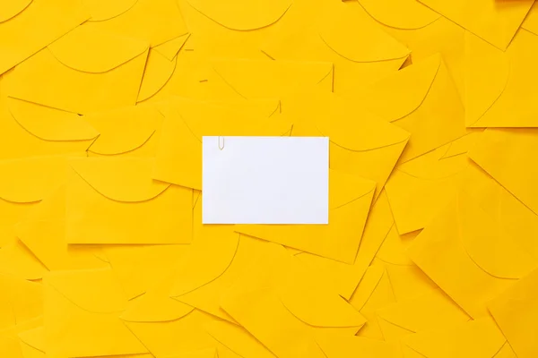 Sarı zarflar masaya saçılmış, beyaz bir kağıtta yazı için yer var. Altı çizili. Üst görünüm.