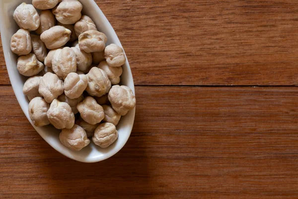 Tahta bir masada beyaz kaşıkta nohut. Mesaj için yer var. Üst görünüm