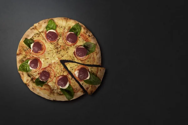 Mozzarella peynirli pizza, domates ve gri taş bir masada dilimlenmiş fesleğen. Üst Manzara. Metin için boşluk.