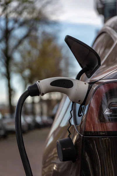 Modern electric car being charged in the dutch street, Close up of the plugged charging plug