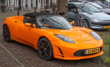 Amsterdam, Hollanda, 28.12.2025, 2011 yılından itibaren birinci nesil elektrikli elektrikli spor araba Tesla Roadster turuncu renkli.