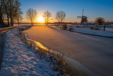 Günbatımına kadar Abcoude 'da tarihi rüzgar değirmeni ve donmuş nehir Gein ile Hollanda kışı manzarası