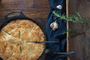 Dökme demir bir tavada altın kabuklu taze pişmiş börek. Taze sarımsak ve bitkiler..