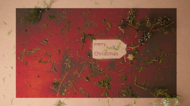 Karmaşık yeşil dalları ve koyu kahverengi arka planda dağınık ardıç meyveleri olan kağıt bir hediye etiketinde retro titreşimler olan mutlu Noeller mesajı..