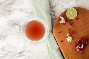 Beyaz ve gri mermer yüzeyde şekerli martini bardağıyla nar kokteyli..