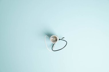 Parlak mavi arkaplanda beyaz ve siyah kablolu yeni bir ışık soketinin üst görünümü