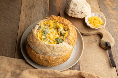 Brokoli çedar çorbası. Ekşi ekmek kasesinde kahverengi peçete ve antika kaşık ile ahşap masada.