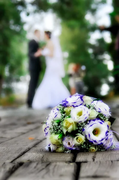 Весільний букет на фоні нареченої і нареченого — стокове фото