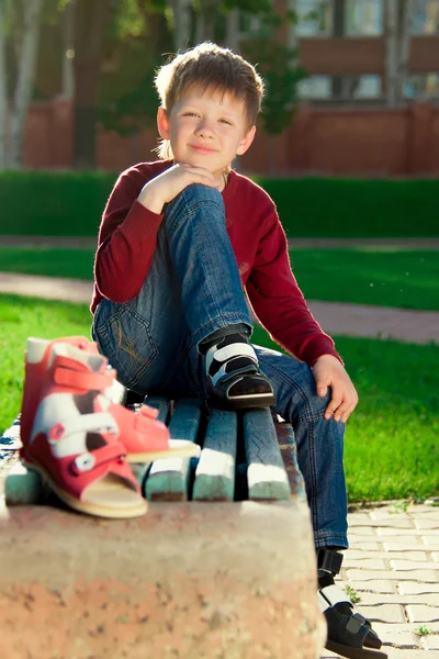 Мальчик сидит на скамейке в парке — стоковое фото