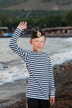 garrison kap ve çizgili yelek denize yakın duran çocuk