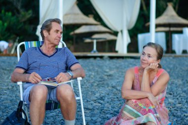 Adam ve kadın sahilde oturuyor.