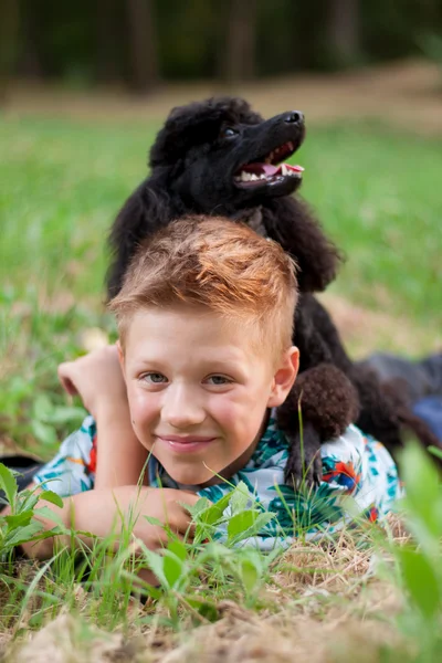 Мальчик с черным пуделем на природе — стоковое фото
