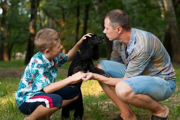 Pai e filho, e um poodle preto — Fotografia de Stock