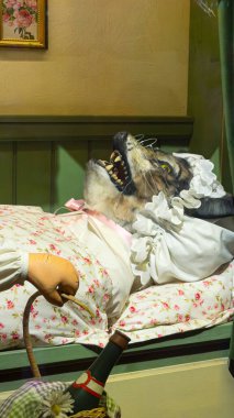 Kırmızı başlıklı gri bir kurt büyükanne kılığında beşikte yatıyor.