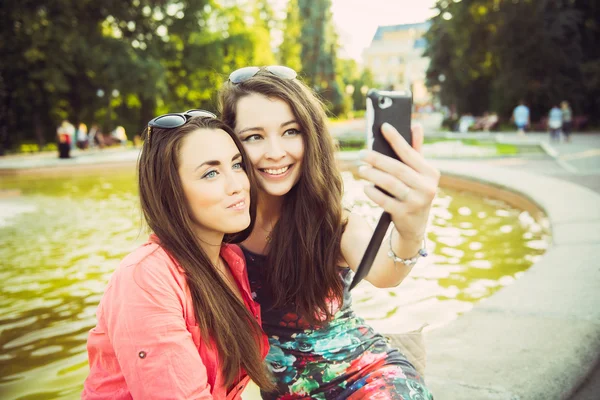 Dışarıda selfie çeken iki genç kadın.