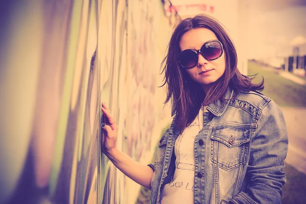 Chica en gafas de sol cerca de la pared de graffiti —  Fotos de Stock