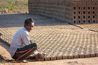 TIKAMGARH, MADHYA PRADESH, INDIA - 11 AĞUSTOS 2021: Kalıplı ve ıslak kilden ev tuğlaları yapan Hintli adam.