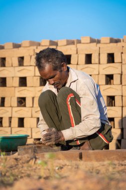 TIKAMGARH, MADHYA PRADESH, INDIA - 11 AĞUSTOS 2021: Kalıplı ve ıslak kilden ev tuğlaları yapan Hintli adam.