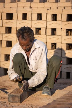 TIKAMGARH, MADHYA PRADESH, INDIA - 11 AĞUSTOS 2021: Kalıplı ve ıslak kilden ev tuğlaları yapan Hintli adam.