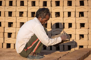 TIKAMGARH, MADHYA PRADESH, INDIA - 11 AĞUSTOS 2021: Kalıplı ve ıslak kilden ev tuğlaları yapan Hintli adam.