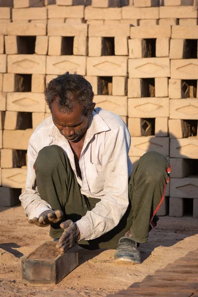 TIKAMGARH, MADHYA PRADESH, INDIA - 11 AĞUSTOS 2021: Kalıplı ve ıslak kilden ev tuğlaları yapan Hintli adam.