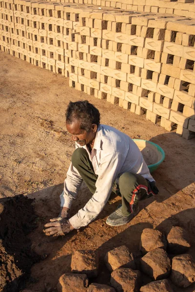 TIKAMGARH, MADHYA PRADESH, INDIA - 11 AĞUSTOS 2021: Kalıplı ve ıslak kilden ev tuğlaları yapan Hintli adam.