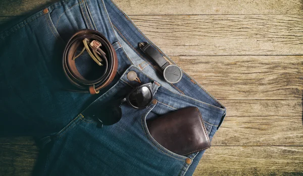 Jeans plånbok och bälte klockor glasögon på trä bakgrund, topp vi Stockfoto