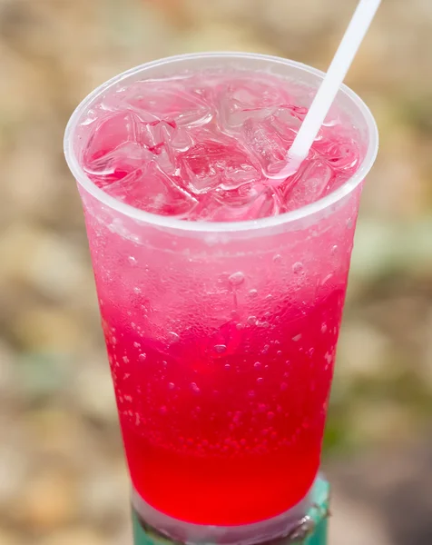 Red cool drink in plastic cup with water bubble against brown ou — Stock Photo, Image