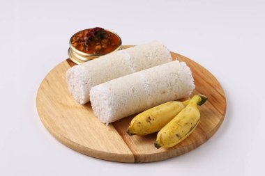 Puttu / Çiğ pirinç puttu / Arisi Maavu Puttu ve chana körili / kadala körili-Kerala özel kahvaltı öğeleri, çiğ pirinç unu kullanılarak yapılan, beyaz arkaplanda muz ve ahşap bir zeminde yerleştirilmiş ideal bir kombinasyon.