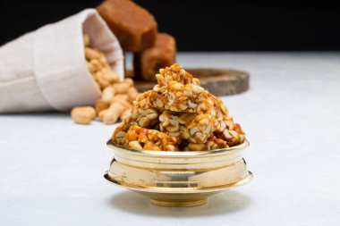 Fıstıklı gofret, çok sağlıklı ve lezzetli bir atıştırmalık, arka planda bir çuval fıstık ve jaggery ile beyaz bir dokuya yerleştirilmiş, seçici bir odak.