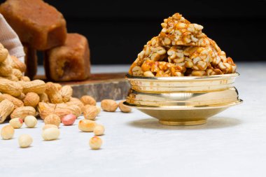 Fıstıklı gofret, çok sağlıklı ve lezzetli bir atıştırmalık, arka planda bir çuval fıstık ve jaggery ile beyaz bir dokuya yerleştirilmiş, seçici bir odak.