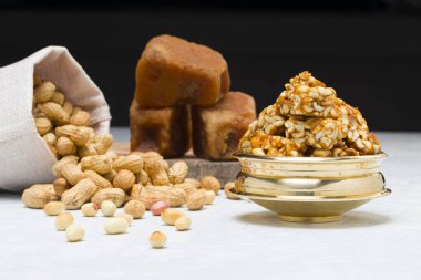 Fıstıklı gofret, çok sağlıklı ve lezzetli bir atıştırmalık, arka planda bir çuval fıstık ve jaggery ile beyaz bir dokuya yerleştirilmiş, seçici bir odak.