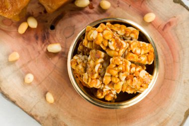 Fıstık ezmesi, kıtır kıtır fıstık, çok sağlıklı ve lezzetli bir atıştırmalık, pirinç bir kaba yerleştirilmiş, arka planda biraz fıstık ve jaggery, seçici bir odak.