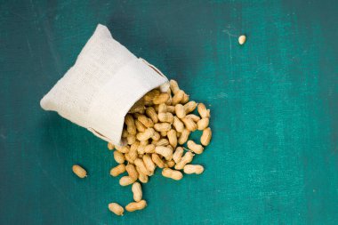 Fıstık ezmesi çok sağlıklıdır. Koyu yeşil desenli bir arka plana dökülen çuvala konur..