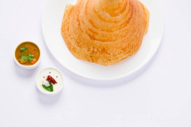 Dosa _, Ghee rosto Dosa, ünlü Güney Hindistan kahvaltı öğesi geleneksel olarak kast demir tavasından yapılır ve beyaz bir arka planda sambar ve hindistan cevizi turşusuyla izole edilmiş beyaz bir tabakta düzenlenir..