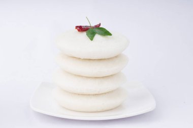 Idly ya da Idli, Güney Hindistan ana kahvaltısı kırmızı acı biber ve köri yapraklarıyla süslenmiş, beyaz arka planda güzelce düzenlenmiş, izole edilmiş..