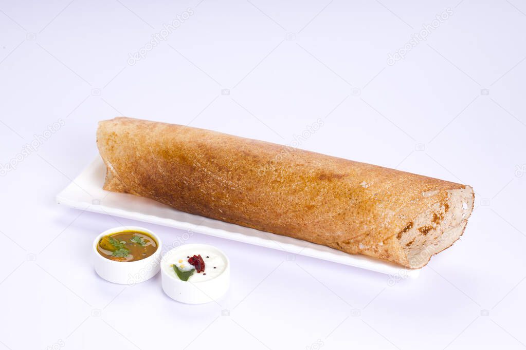 Dosa _Ghee roast Dosa,famous south Indian breakfast item which is made in caste iron pan in traditional way and arranged on a white basewith side dish ,on a white background ,isolated.