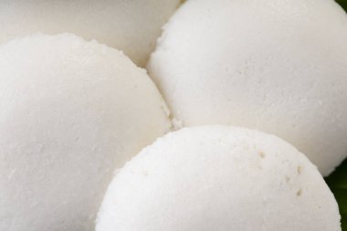 Idly ya da Idli, Güney Hindistan ana kahvaltı öğesi. Beyaz arka planda taze yeşil muz yaprağı ile güzelce düzenlenmiş..