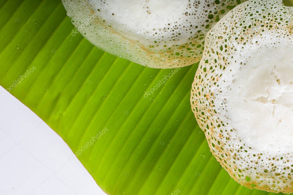 Appam or velliappam or kallappam  or paalappam, tasty delicious  breakfast item in south india or malabar area,made using raw rice and a good combination for veg and non veg currys ,placed on fresh green banana leaf with white background.